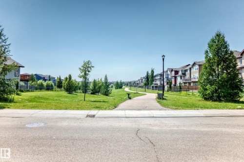 Paved pathway bordered by manicured green spaces and mature trees - 5280 21 Avenue Sw, Edmonton, AB - Outdoor