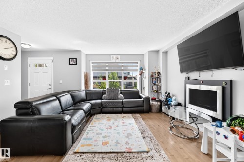 Spacious living area featuring light wood-finish flooring and light gray painted walls - 5280 21 Avenue Sw, Edmonton, AB - Indoor Photo Showing Living Room