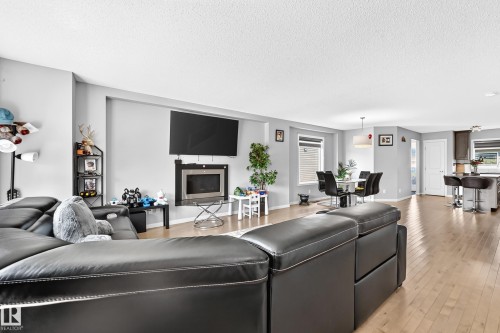 Open-concept living area featuring light wood-finish flooring, a built-in fireplace, and recessed wall space for entertainment - 5280 21 Avenue Sw, Edmonton, AB - Indoor Photo Showing Living Room With Fireplace