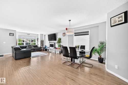 Spacious open-concept living area featuring light wood-finish flooring and light gray walls - 5280 21 Avenue Sw, Edmonton, AB - Indoor Photo Showing Other Room