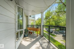 Private balcony with modern glass railing, durable concrete flooring, and surrounding mature trees - 