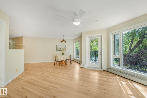 Private balcony with modern glass railing, durable concrete flooring, and surrounding mature trees - #206, 9905 112 St Nw, Edmonton, AB - Outdoor With Balcony With Exterior