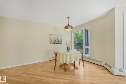 Balcony featuring glass panel railings, textured flooring, and a white paneled exterior - #206, 9905 112 St Nw, Edmonton, AB - Outdoor With Balcony With Exterior
