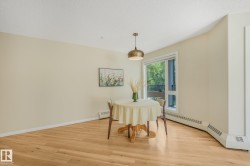 Bright dining area featuring laminate flooring, a contemporary ceiling light fixture, a large window with a balcony visible, and baseboard heating - 