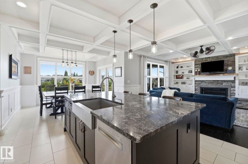 Spacious kitchen island featuring a farmhouse sink and granite countertop - 3 Garneau Gate, Spruce Grove, AB - Indoor Photo Showing Kitchen With Fireplace With Upgraded Kitchen