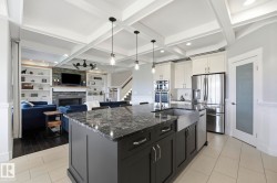 Kitchen island with dark cabinetry, stone countertop, and farmhouse sink - 