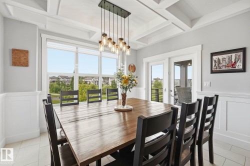 Dining area featuring a coffered ceiling, wainscoting, large windows, and double French doors opening to an exterior space - 3 Garneau Gate, Spruce Grove, AB - Indoor Photo Showing Dining Room