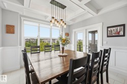Dining area featuring a coffered ceiling, wainscoting, large windows, and double French doors opening to an exterior space - 