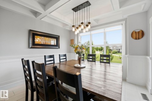 Dining area featuring a coffered ceiling, a multi-bulb chandelier, large windows, chair rail molding, and paneled wainscoting - 3 Garneau Gate, Spruce Grove, AB - Indoor Photo Showing Dining Room