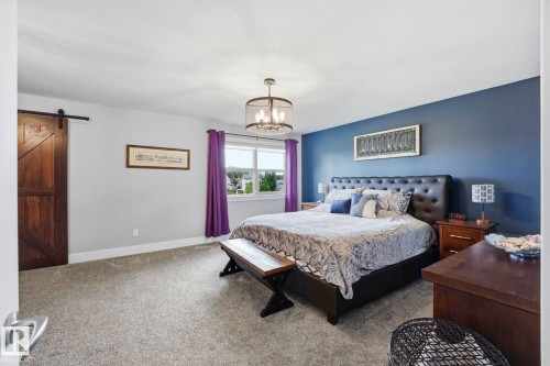 Spacious room featuring gray carpeting, a window with exterior views, and a contemporary chandelier - 3 Garneau Gate, Spruce Grove, AB - Indoor Photo Showing Bedroom