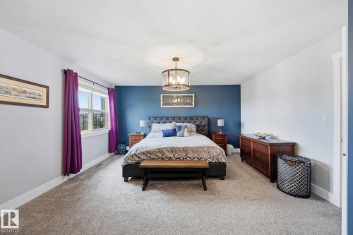 Spacious room featuring neutral carpeting, a prominent accent wall, and a large window with white trim - 3 Garneau Gate, Spruce Grove, AB - Indoor Photo Showing Bedroom