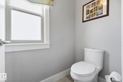 Bathroom featuring a white toilet, light gray walls, and white trim - 