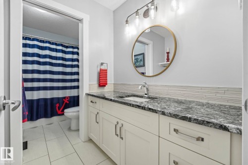 Bathroom vanity featuring a dark patterned countertop, an undermount sink, and brushed nickel fixtures - 3 Garneau Gate, Spruce Grove, AB - Indoor Photo Showing Bathroom