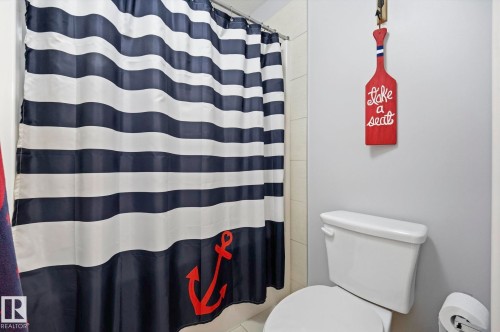 White ceramic toilet with a concealed trapway and a chrome flush lever - 3 Garneau Gate, Spruce Grove, AB - Indoor Photo Showing Bathroom