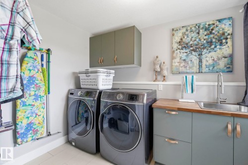 Dedicated laundry area featuring a stainless steel sink, wood-finish countertop, and built-in cabinetry - 3 Garneau Gate, Spruce Grove, AB - Indoor Photo Showing Laundry Room