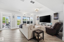 Spacious living area featuring wood-finish flooring, recessed lighting, and a modern built-in entertainment center - 