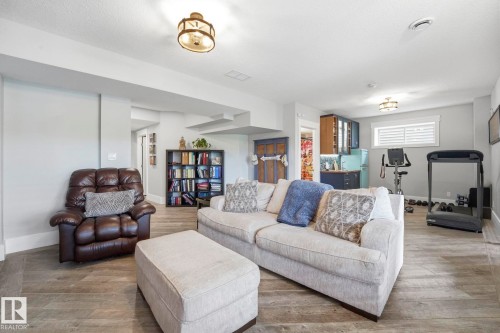Spacious room featuring wood-finish flooring, recessed lighting, and a built-in wet bar with cabinetry - 3 Garneau Gate, Spruce Grove, AB - Indoor Photo Showing Living Room