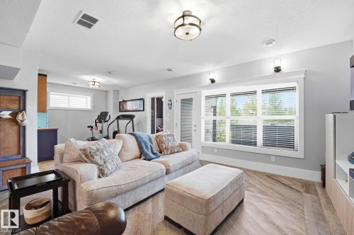 Spacious lower level featuring herringbone wood-finish flooring, recessed lighting, and wall sconces - 3 Garneau Gate, Spruce Grove, AB - Indoor Photo Showing Living Room