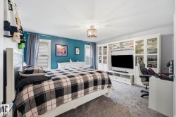 Bedroom featuring a built-in entertainment center with display shelving, a ceiling-mounted light fixture, white trim, and light gray carpeting - 