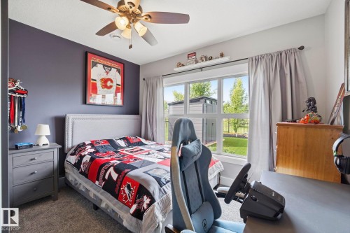 Bedroom featuring a ceiling fan with integrated lighting, a window offering exterior views, a built-in wall shelf, and soft carpeting - 3 Garneau Gate, Spruce Grove, AB - Indoor Photo Showing Bedroom