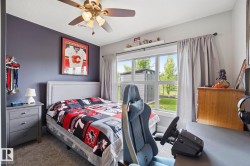 Bedroom featuring a ceiling fan with integrated lighting, a window offering exterior views, a built-in wall shelf, and soft carpeting - 