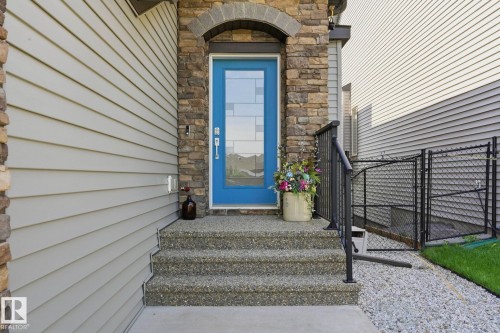Entryway featuring stone veneer accents, light gray horizontal siding, and a blue door with decorative glass inserts - 3 Garneau Gate, Spruce Grove, AB - Outdoor With Exterior