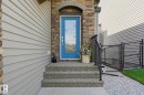 Entryway featuring stone veneer accents, light gray horizontal siding, and a blue door with decorative glass inserts - 3 Garneau Gate, Spruce Grove, AB  - Outdoor With Exterior 