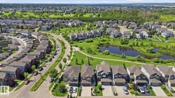 Residential development featuring a pond with surrounding greenery, curved roadways, manicured lawns, and varied architectural home styles - 