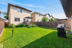Expansive rear lawn featuring a wooden privacy fence, a raised wooden deck, and vinyl siding on the house exterior - 