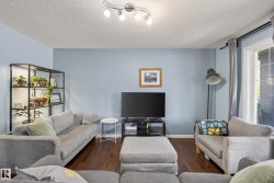Living area featuring wood-finish flooring, light blue wall paint, and a textured white ceiling - 