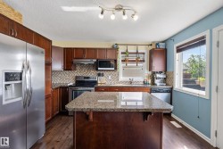 Kitchen featuring a central island with a granite-style countertop, wood-finish flooring, and dark wood cabinetry - 