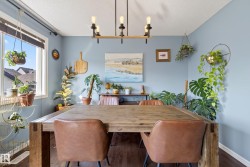 Spacious dining area featuring wood-finish flooring, a contemporary linear chandelier, and ample natural light from a large window - 