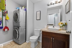 Bathroom featuring a stacked washer and dryer, wood-finish vanity with a vessel sink, square-tile flooring, and a rectangular mirror - 