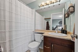 Bathroom featuring a dark wood-finish vanity with a light countertop, an undermount sink, and a large wall-mounted mirror - 