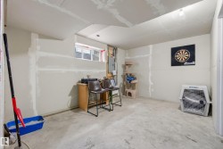 Unfinished basement featuring concrete flooring, partial drywall installation, and a single window for natural light - 