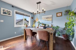 Dining area featuring hardwood flooring, a bright window, and a modern linear chandelier - 