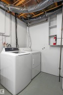 Dedicated laundry area featuring a white top-load washing machine and white dryer unit - 