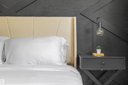 Cream upholstered headboard with geometric paneling, dark textured accent wall, and a black nightstand with a single drawer - 4001 113 Avenue Nw, Edmonton, AB - Indoor Photo Showing Bedroom