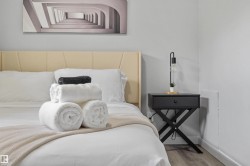 Bedroom featuring a padded headboard, a black nightstand with a single drawer, and wood-finish flooring - 