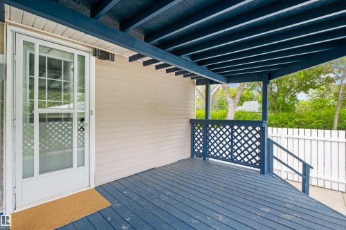Covered deck featuring a blue-painted wood floor, blue lattice railing, and steps leading down - 4001 113 Avenue Nw, Edmonton, AB - Outdoor With Deck Patio Veranda With Exterior