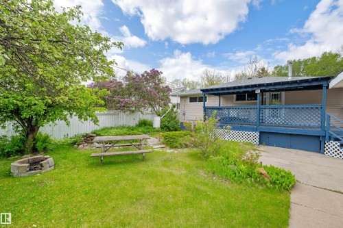 Expansive backyard featuring a covered patio, a fire pit, mature trees, and a privacy fence - 4001 113 Avenue Nw, Edmonton, AB - Outdoor With Deck Patio Veranda
