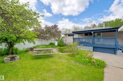 Expansive backyard featuring a covered patio, a fire pit, mature trees, and a privacy fence - 