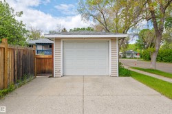 Detached single-car garage featuring a white panel door and tan vinyl siding - 