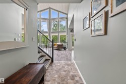 Entryway featuring tile flooring, a dark wood-finish bench, and a staircase with a black metal railing - 