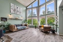 Soaring vaulted ceilings with wood-finish planks, expansive window wall, wood-finish flooring, and light green accent walls - 