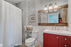Bathroom featuring a red vanity cabinet with white countertop, chrome fixtures, and a rustic wood-framed mirror - 