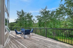 Expansive wooden deck with black metal railings, offering an outdoor living space surrounded by mature trees - 