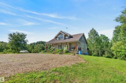 Spacious two-story residence featuring a covered front porch, dormer window, and an expansive gravel driveway - 