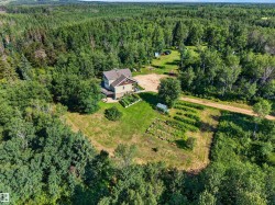 Expansive property featuring a two-story residence with a covered porch, surrounded by mature trees - 