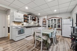 Spacious basement kitchen featuring wood-finish flooring, white shiplap walls, recessed lighting, and a drop ceiling - 